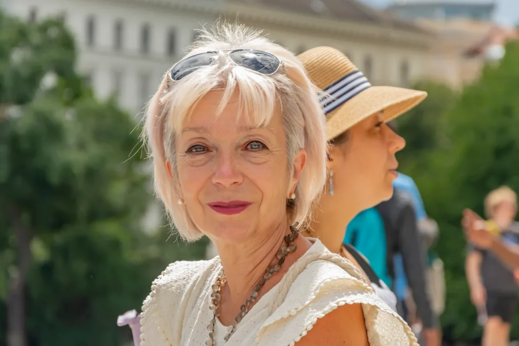 Street portrait of two women, 60-65 years old and 40-45 years old, against a background of people and architecture. Women tourists and travelers.