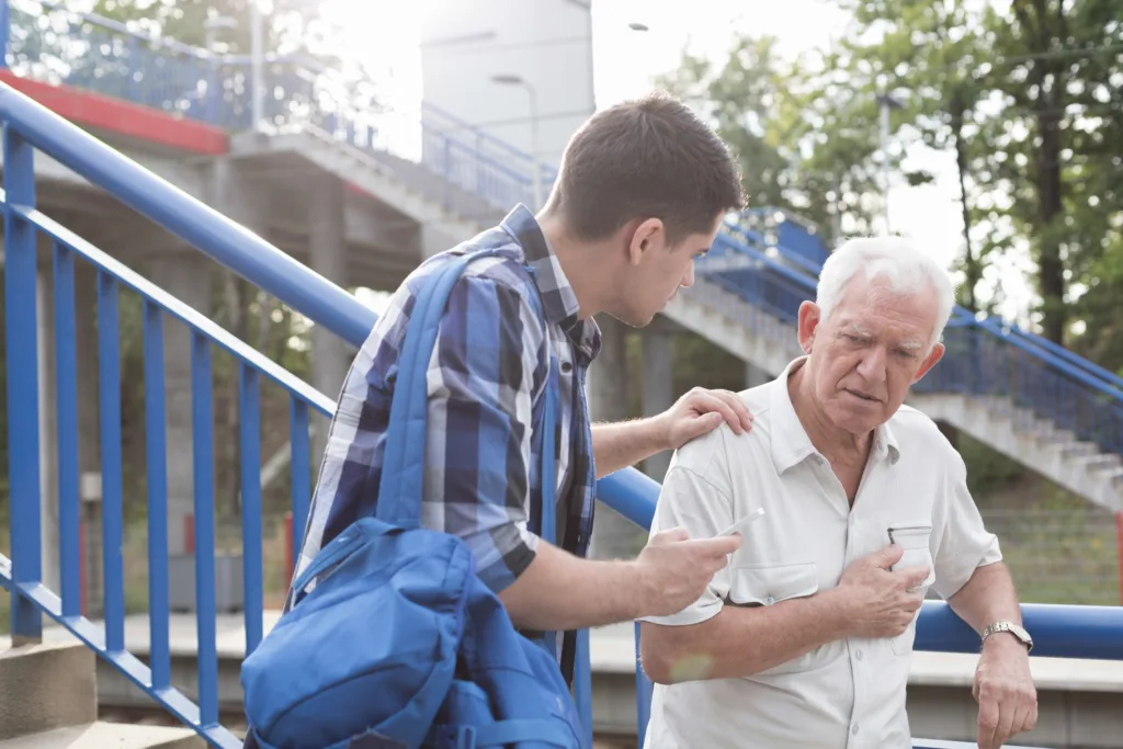 Helpful young man talking to older man grabbing chest