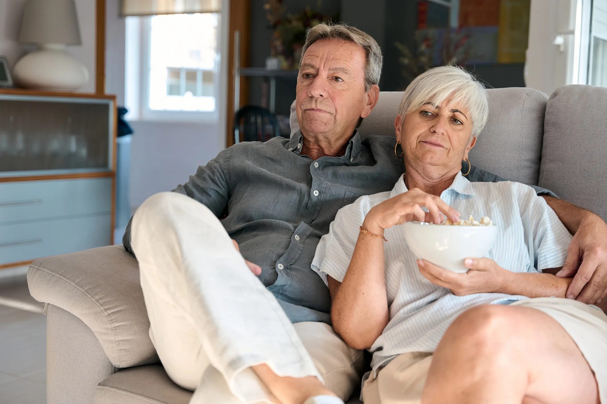Bored senior couple watching television at home