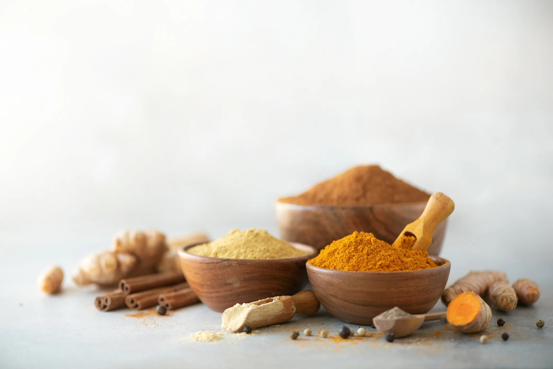 Ingredients for turmeric latte. Ground turmeric, curcuma root, cinnamon, ginger, black pepper on grey background. Spices for ayurvedic treatment. Alternative medicine concept.