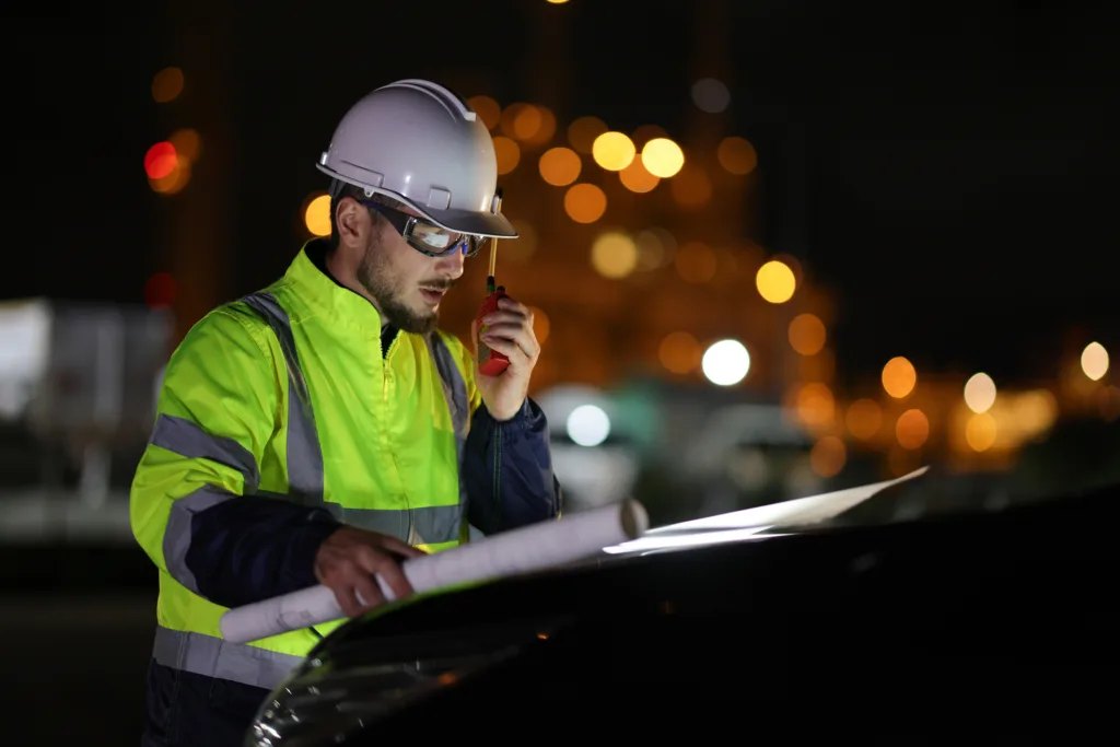The Specialist electrical engineer communicated with the team via walkie-talkie at night against the light of bokeh in the background