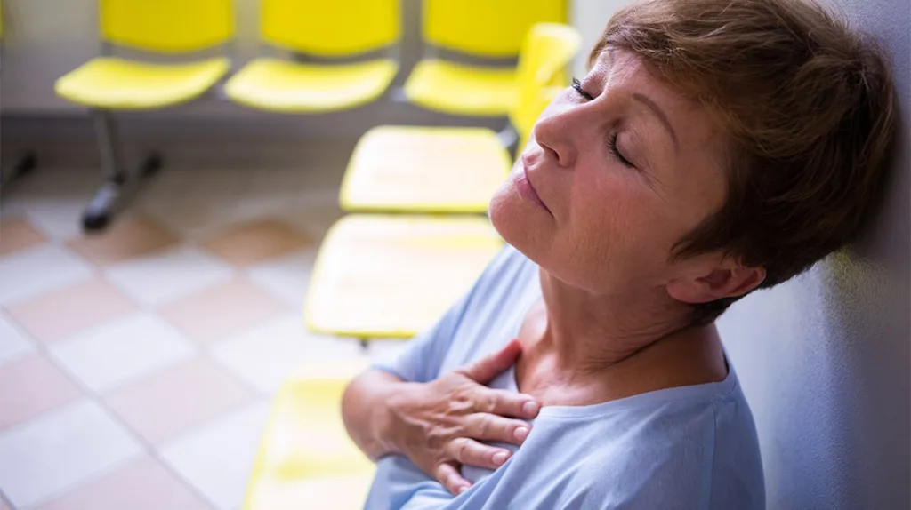 middle aged woman with hand on chest experiencing pain