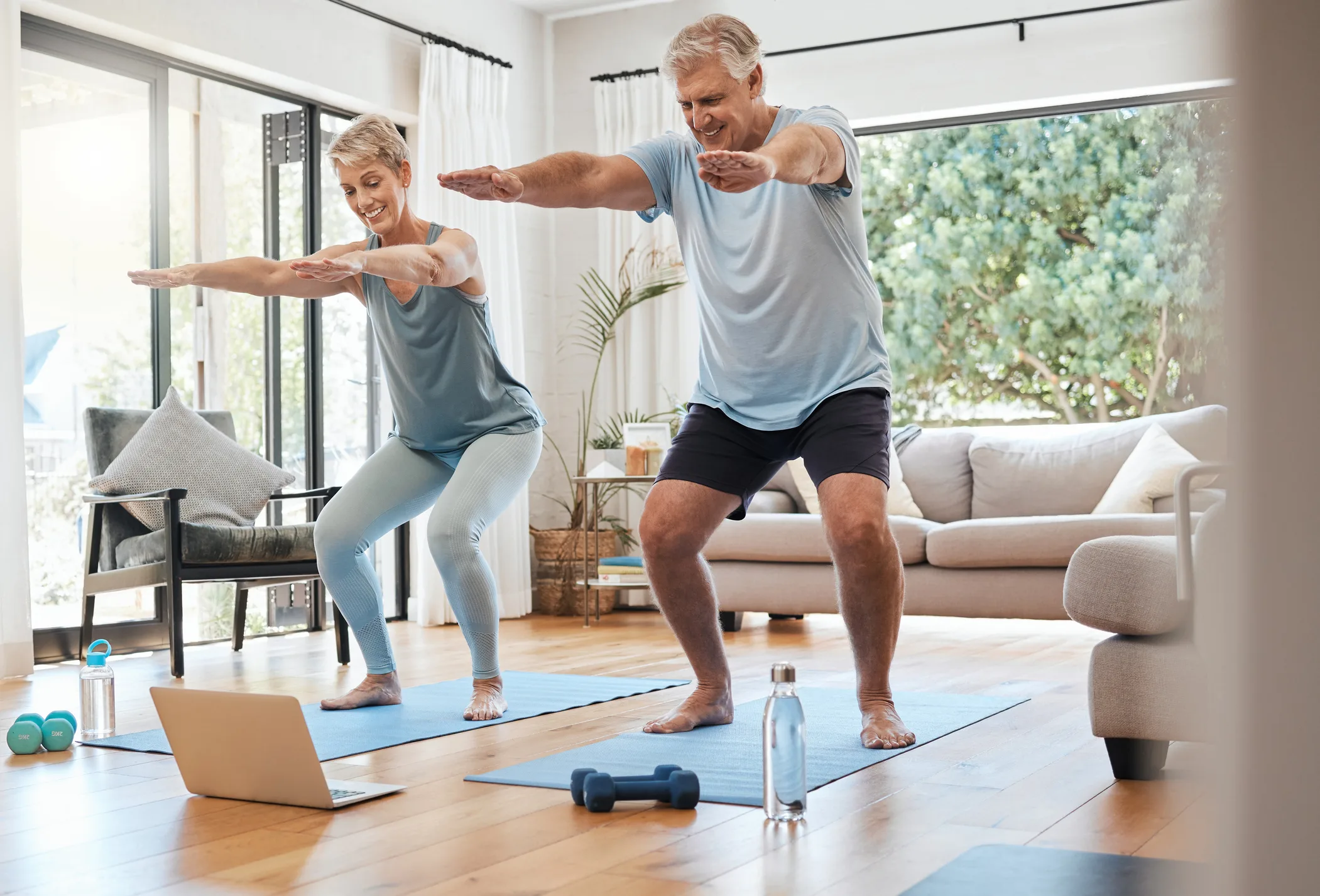 Senior couple in living room exercising while watching streaming video