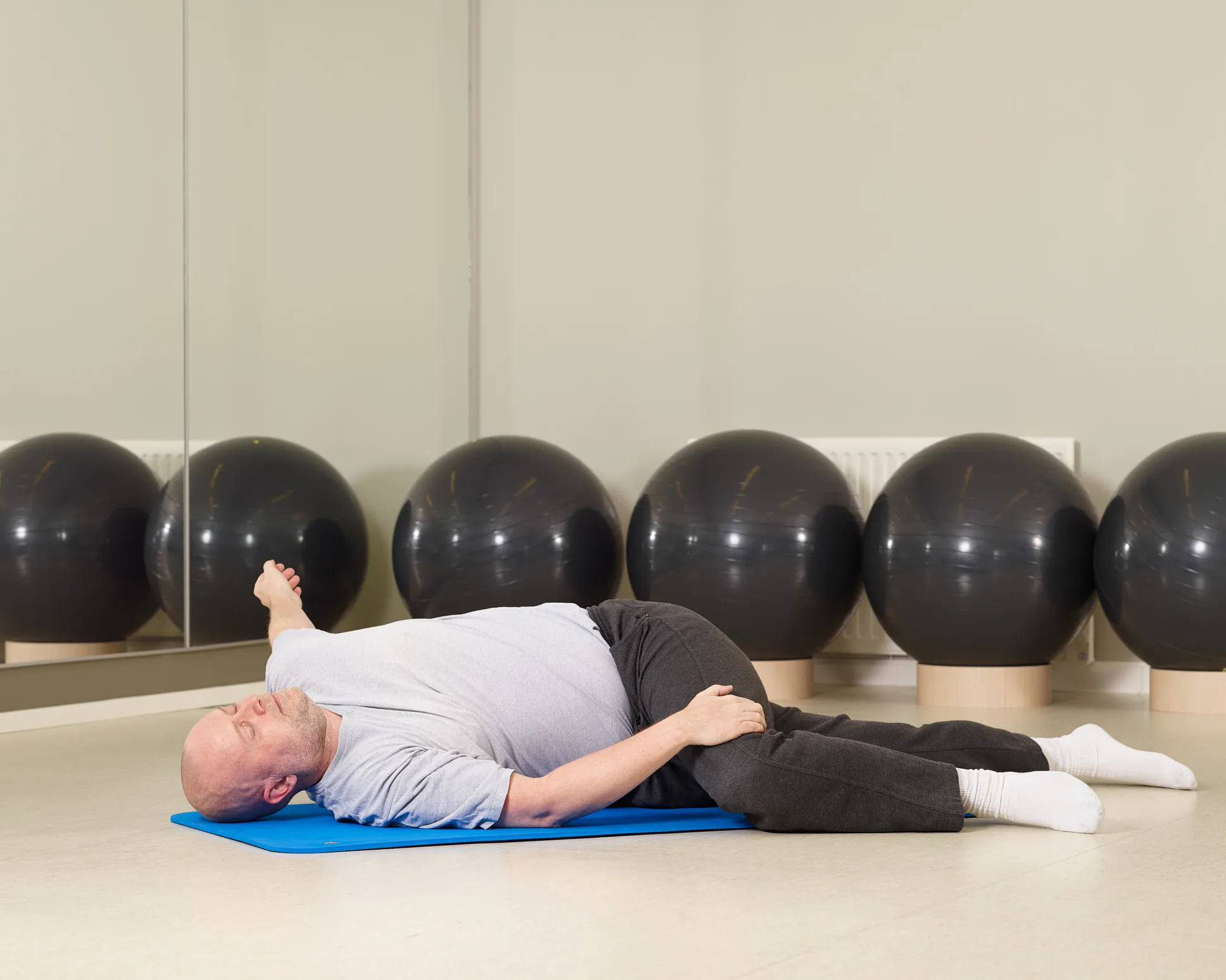 Mature man takes care of his health, he exercise pilates and stretching in a gym