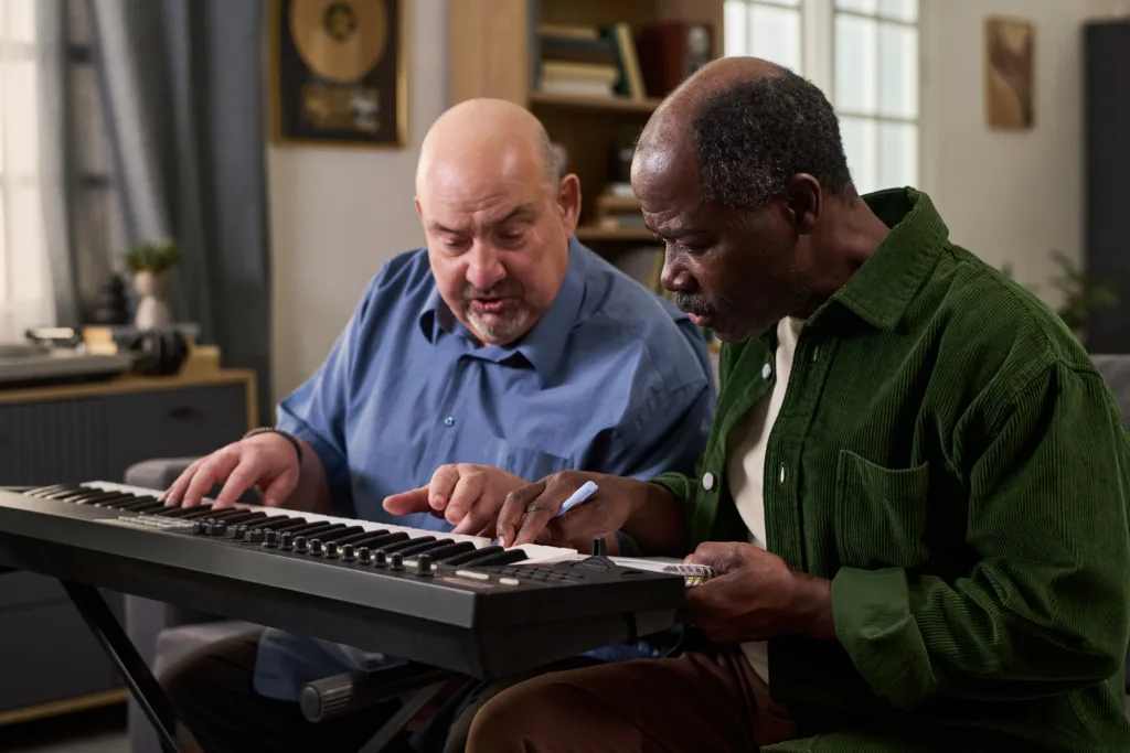 Senior Black Man Practicing Electronic Keyboard with Middle Aged Caucasian Man