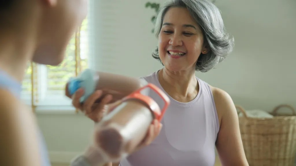 Young adult child active mature middle age old mum drink whey protein shake bottle diet food after home workout. Love health care older aged mom asia elder people happy relax sport protect aging life.