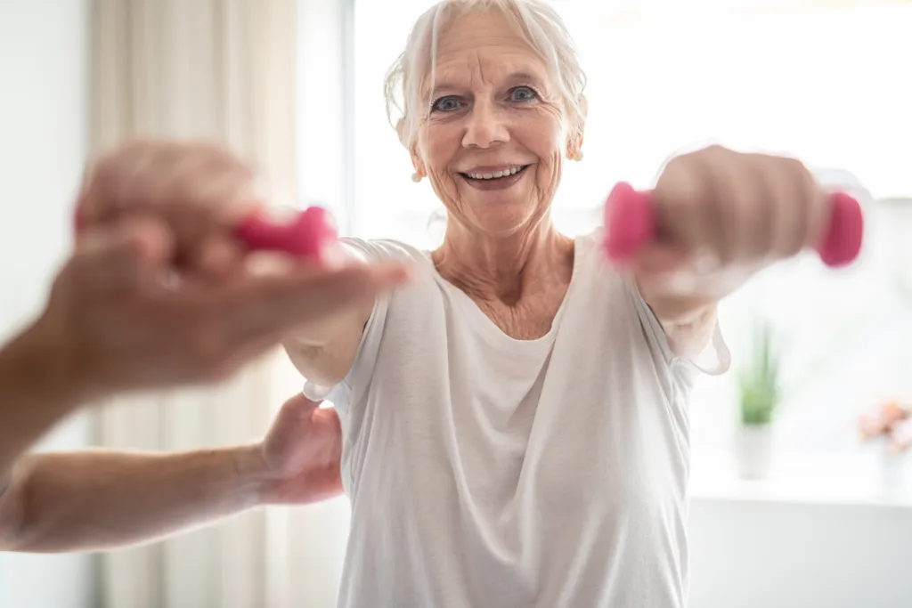 A elderly woman engaging in rehabilitative exercises under the guidance and support of physiotherapist