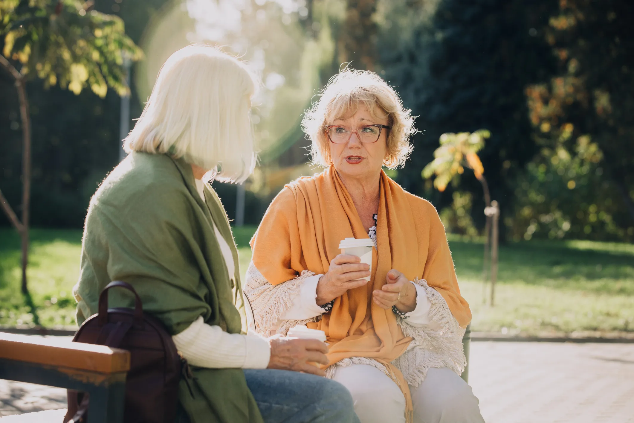 Elderly women talking and drinking coffee in park