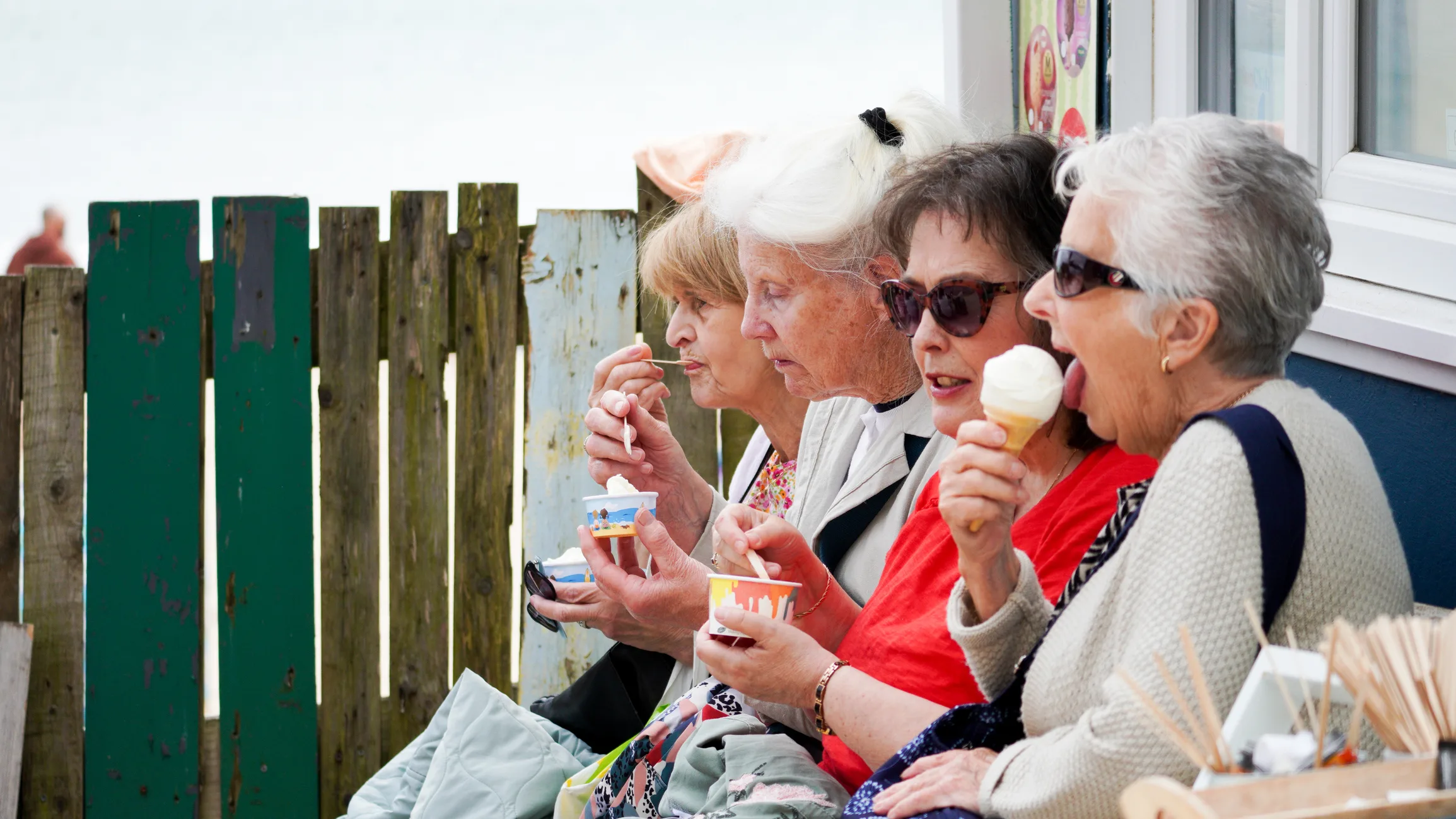 Four senior ladies enjoying an ice-cream by the beach in Tenby