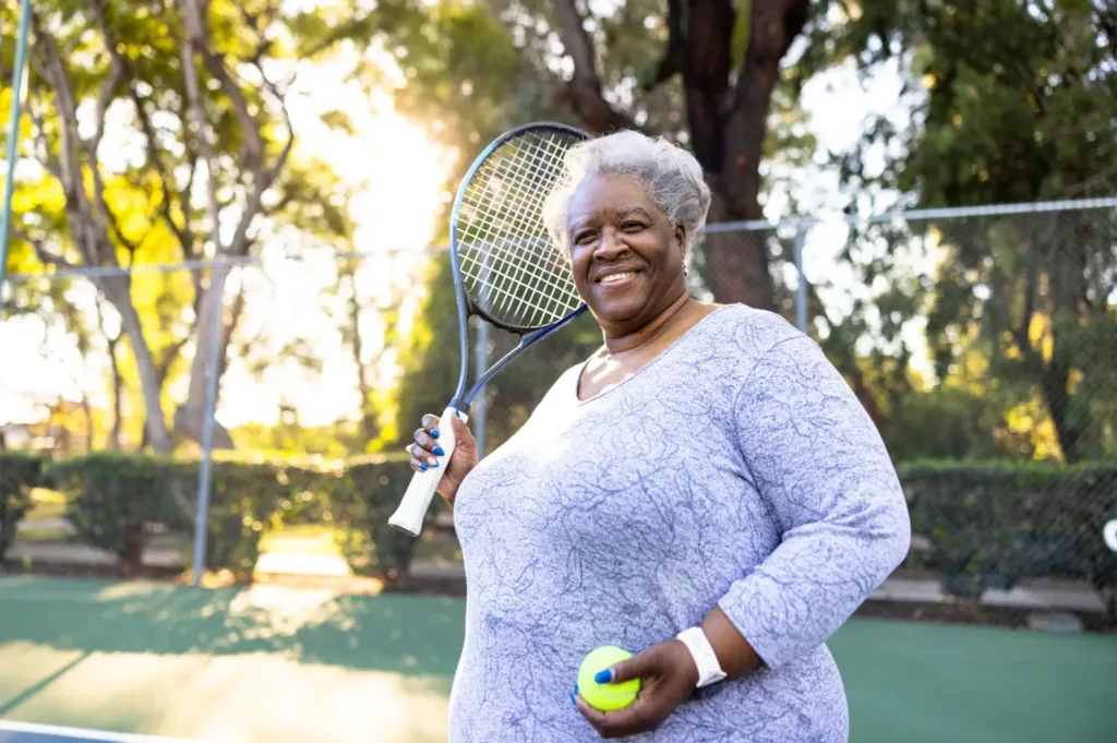 Older overweight African American woman with tennis racket