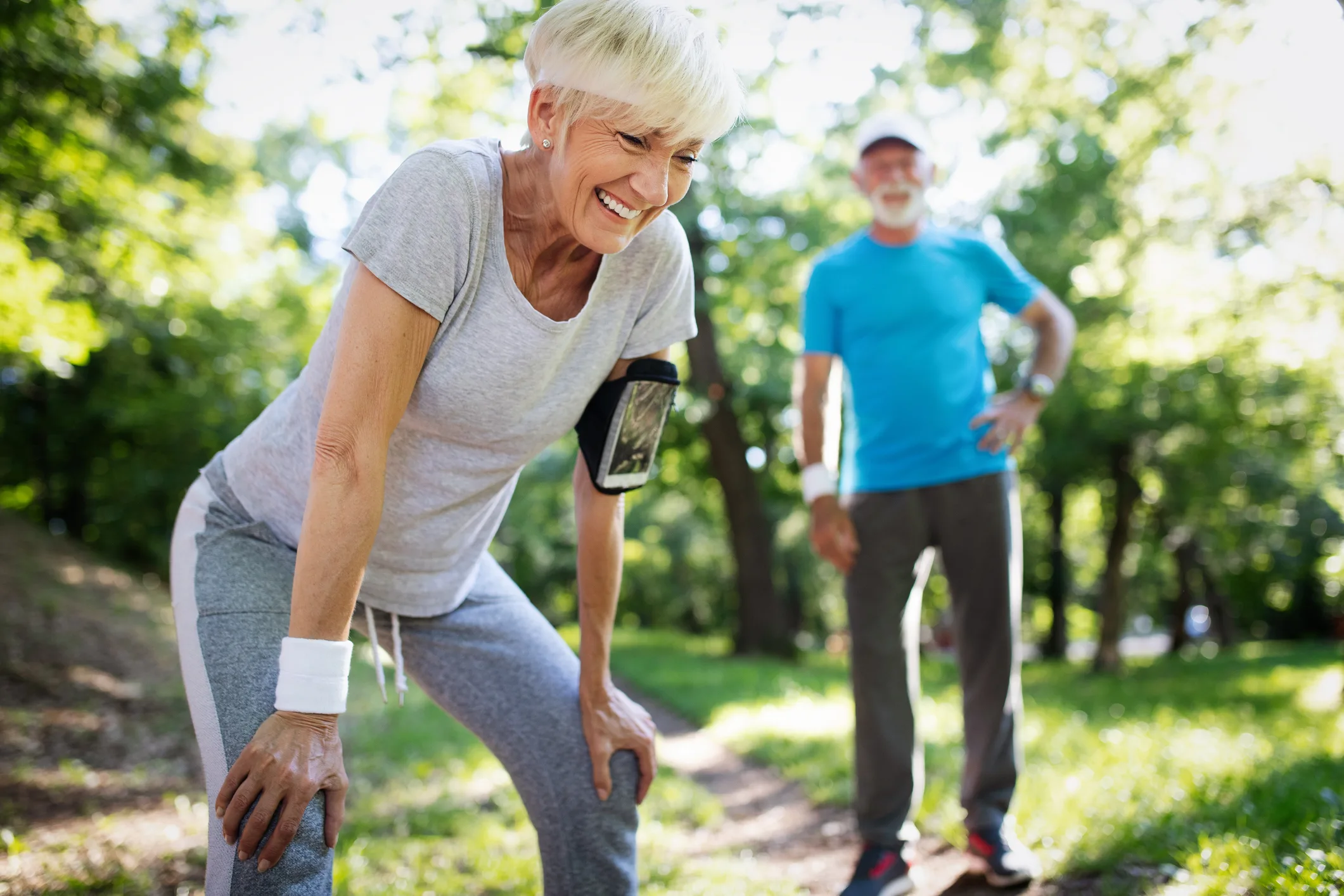 Beautiful senior couple running outside in forest
