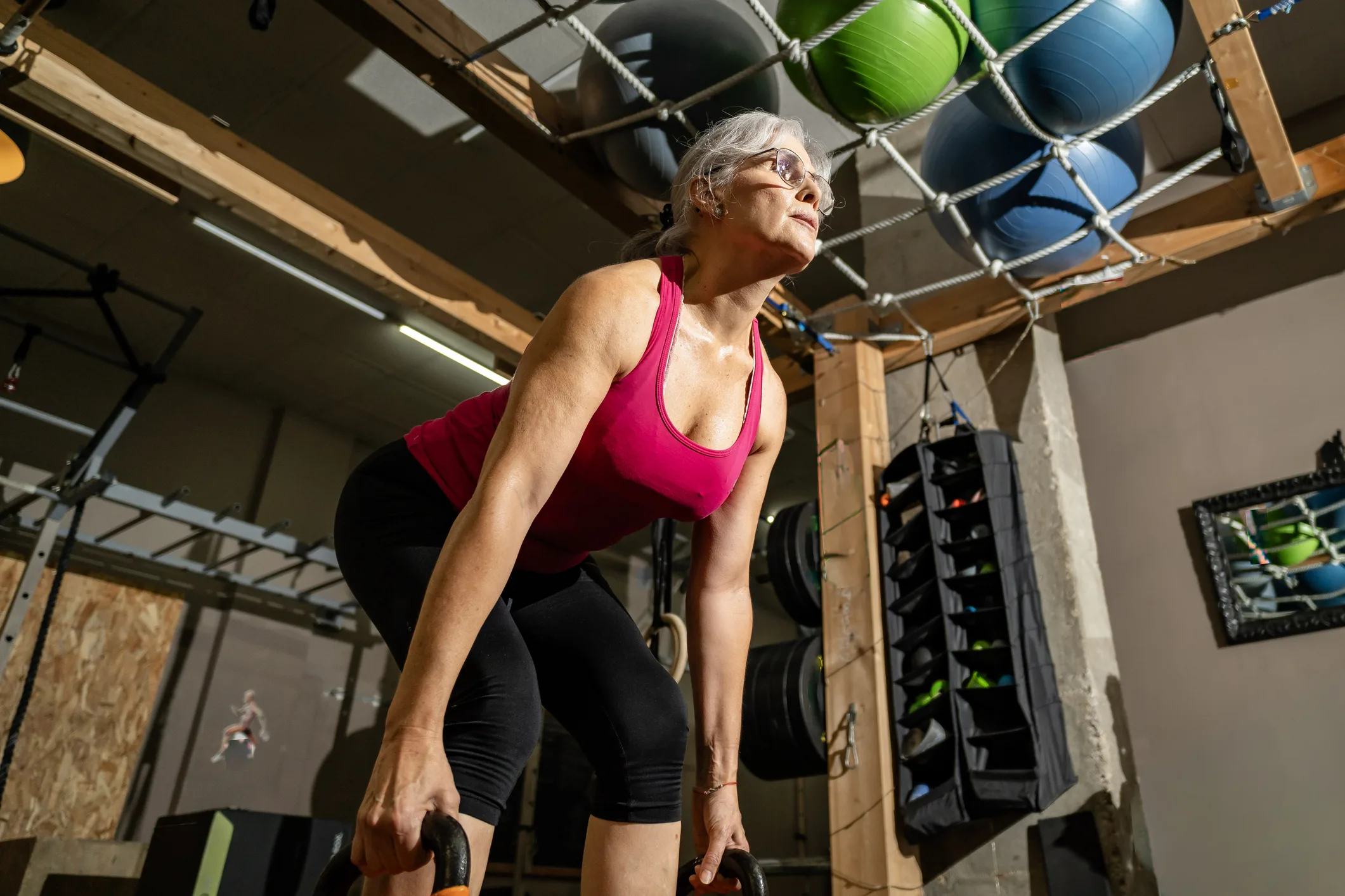 Senior woman training with kettlebells in a gym