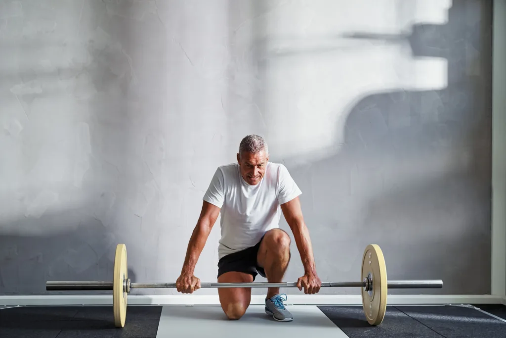 Senior man preparing to lift weights at the gym