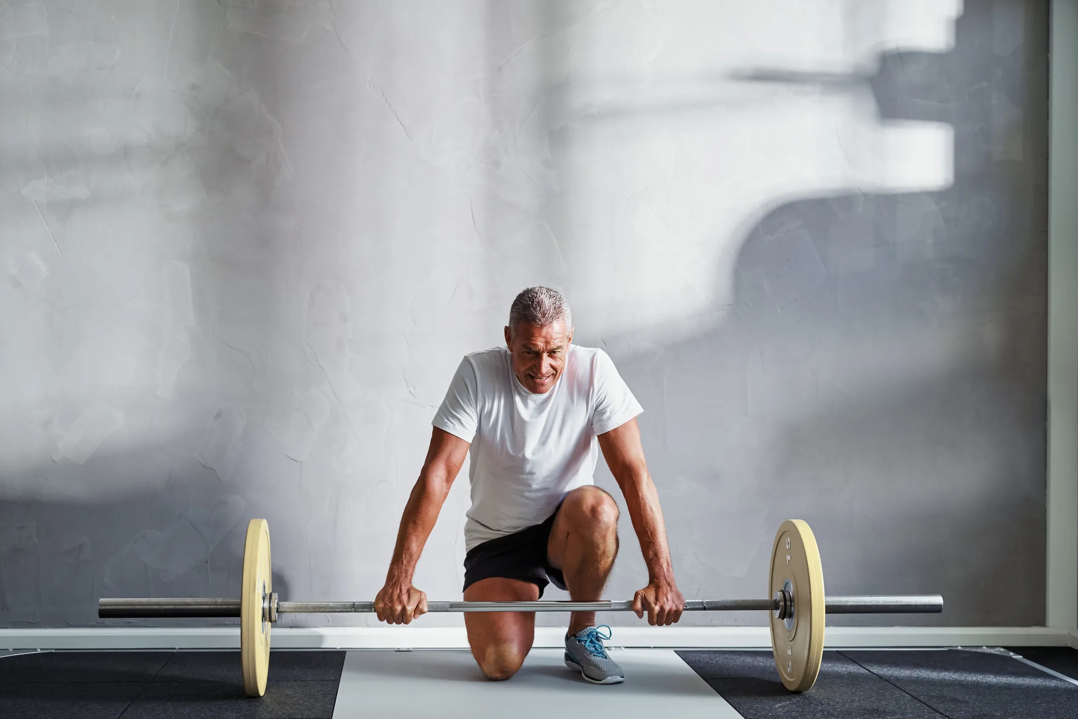 Senior man preparing to lift weights at the gym