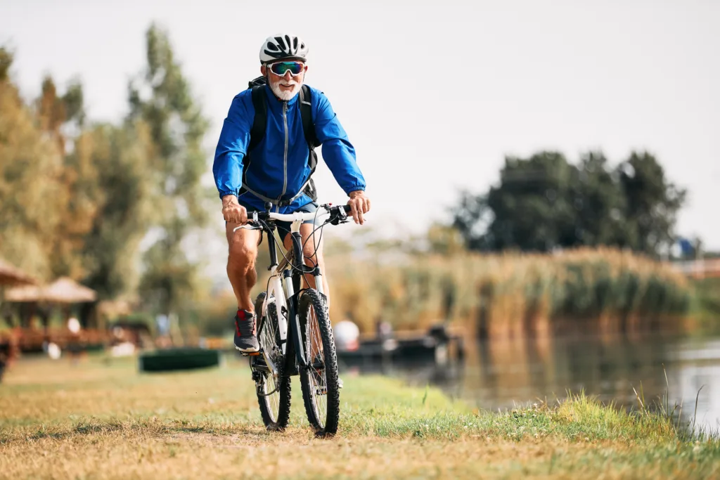 Senior athlete riding mountain bike by the river in nature.