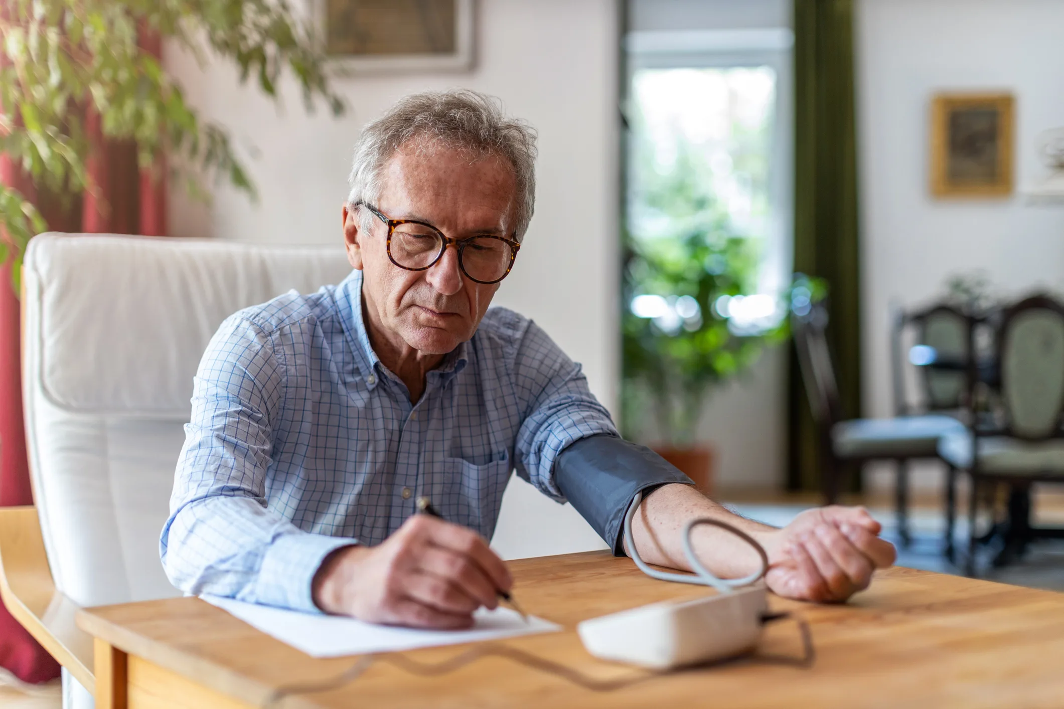 Senior man using medical device to measure blood pressure