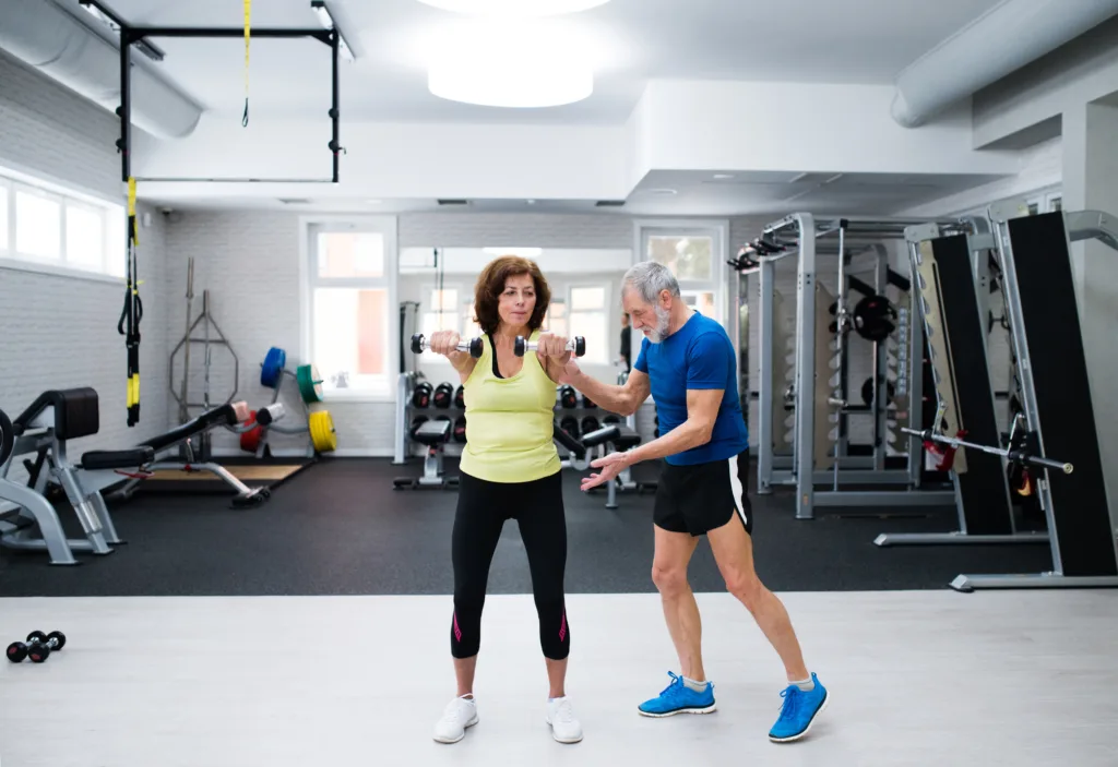 Senior couple in gym working out with weights