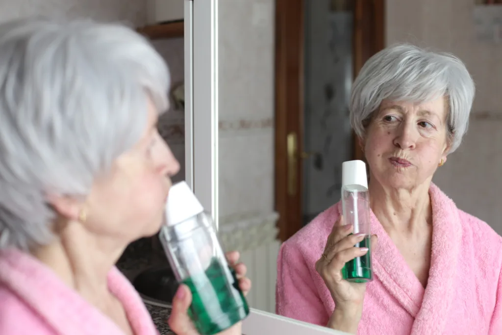 Beautiful senior woman using mouthwash