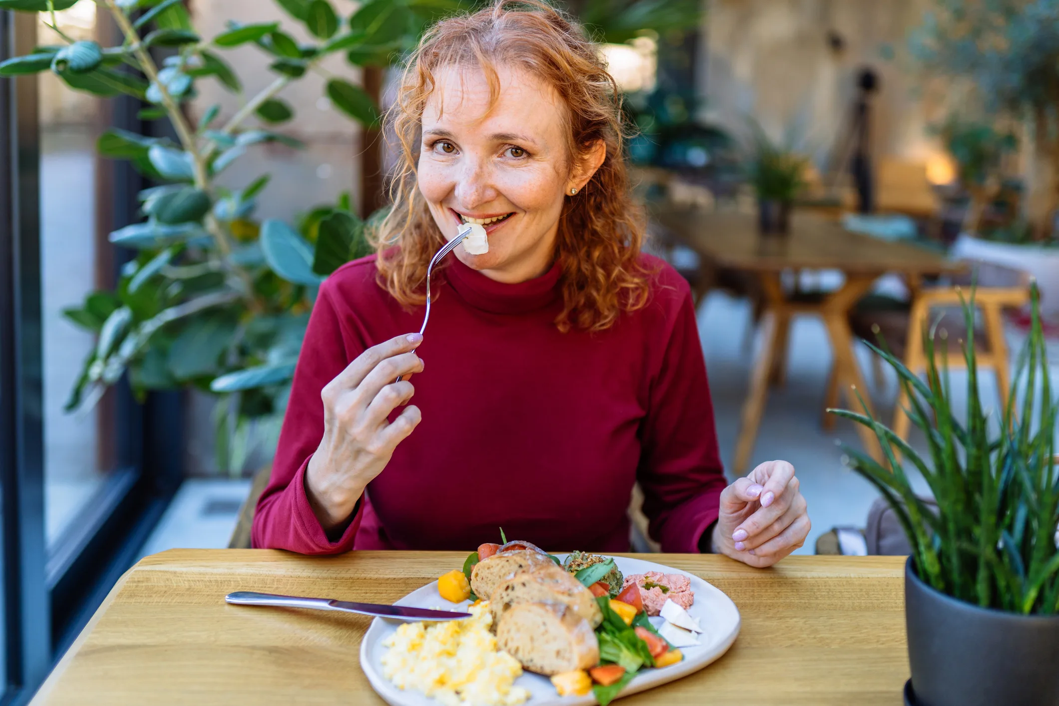 Smiling woman enjoying a healthy breakfast at a cozy cafe