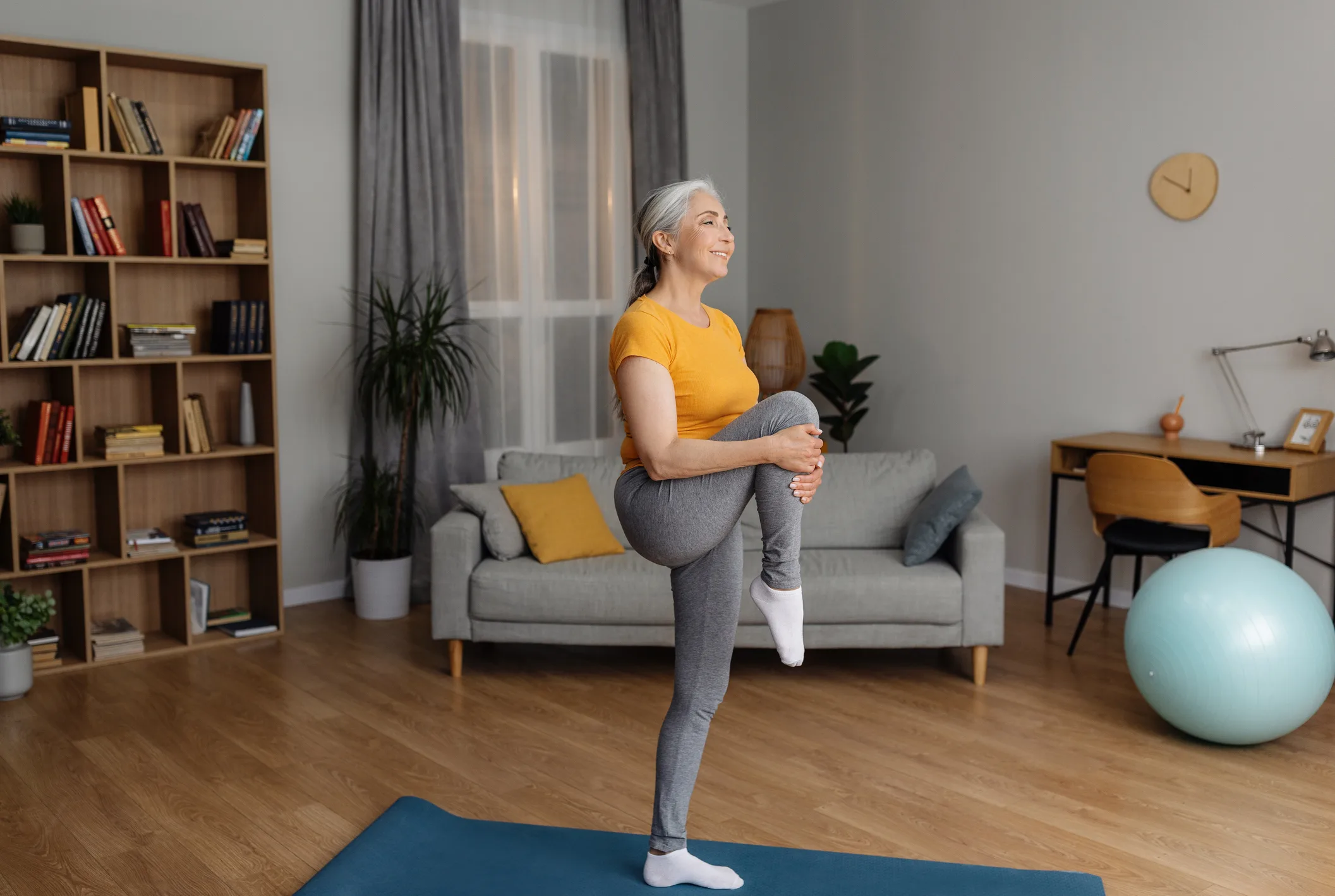 Domestic fitness. Fit senior woman in sportswear doing exercises on yoga mat, stretching her leg on home workout, leading active lifestyle, free space